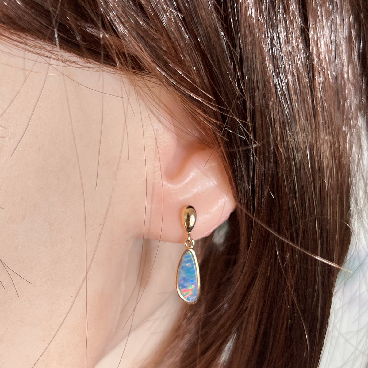 Australian opal doublet earrings worn on the ear, violet, red, green and blue play-of-colour