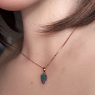 12 x 6.5mm triangular Australian opal doublet pendant worn at the neck, rose gold-plated silver