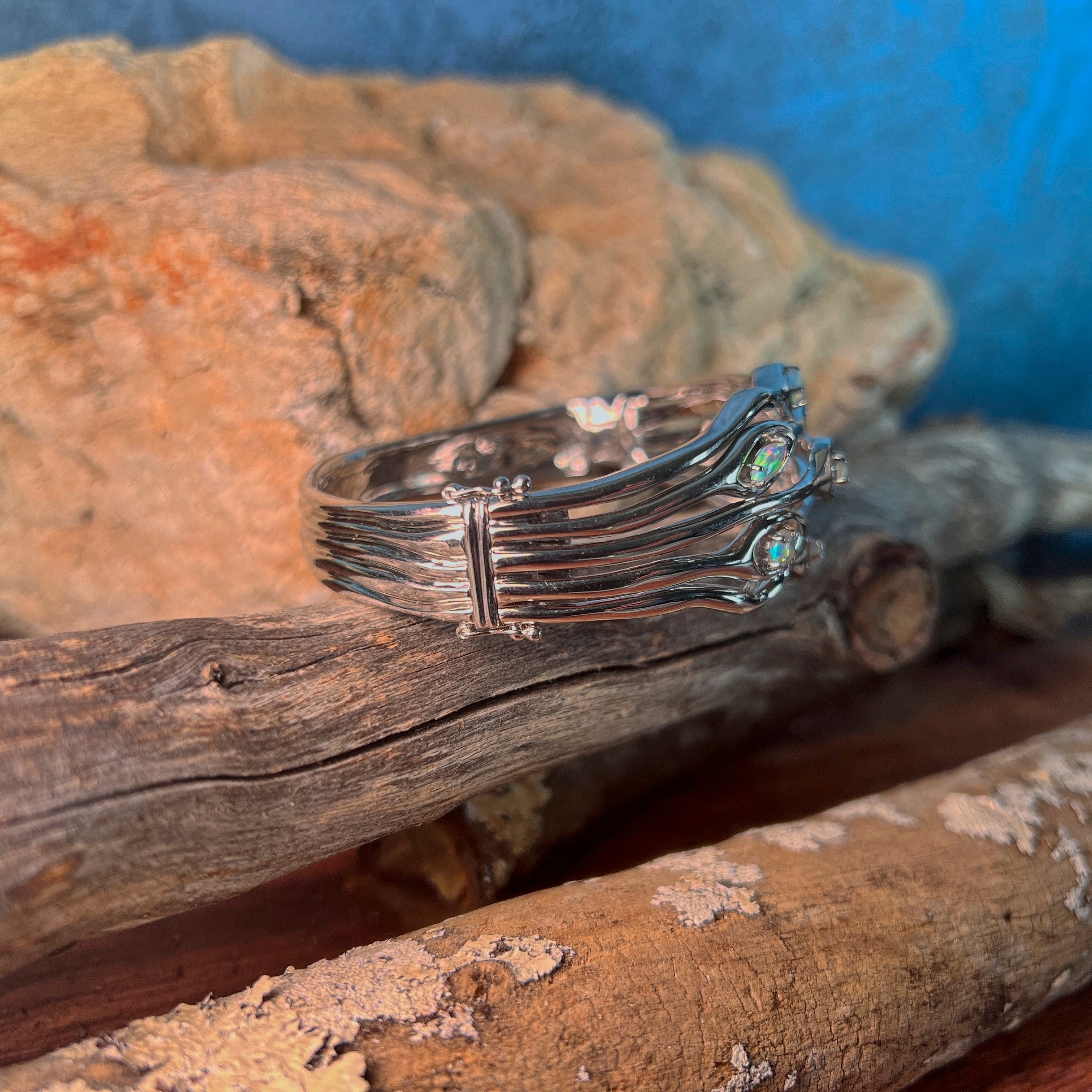 Side profile of the sterling silver wave bangle showing the band and opal setting