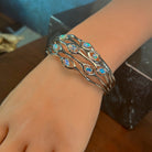 Worn view of the sterling silver wave cut-out opal bangle showing scale