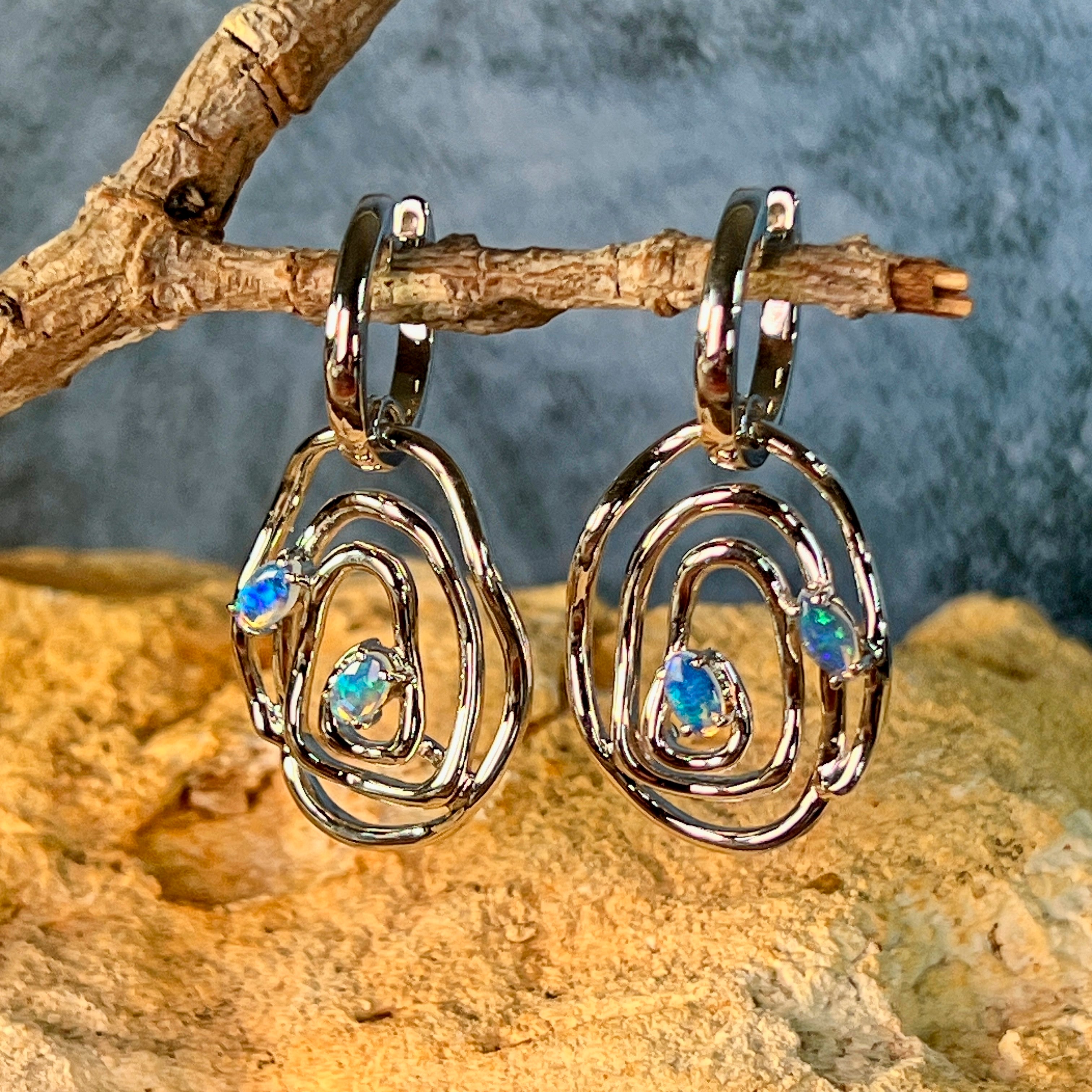 Sterling silver Australian opal circle earrings resting on a branch