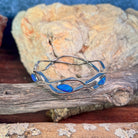 Australian opal doublet bangle in sterling silver against driftwood and sandstone