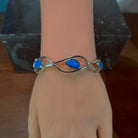 Wave cut-out silver bangle worn, showing how the opal doublet sits on the wrist