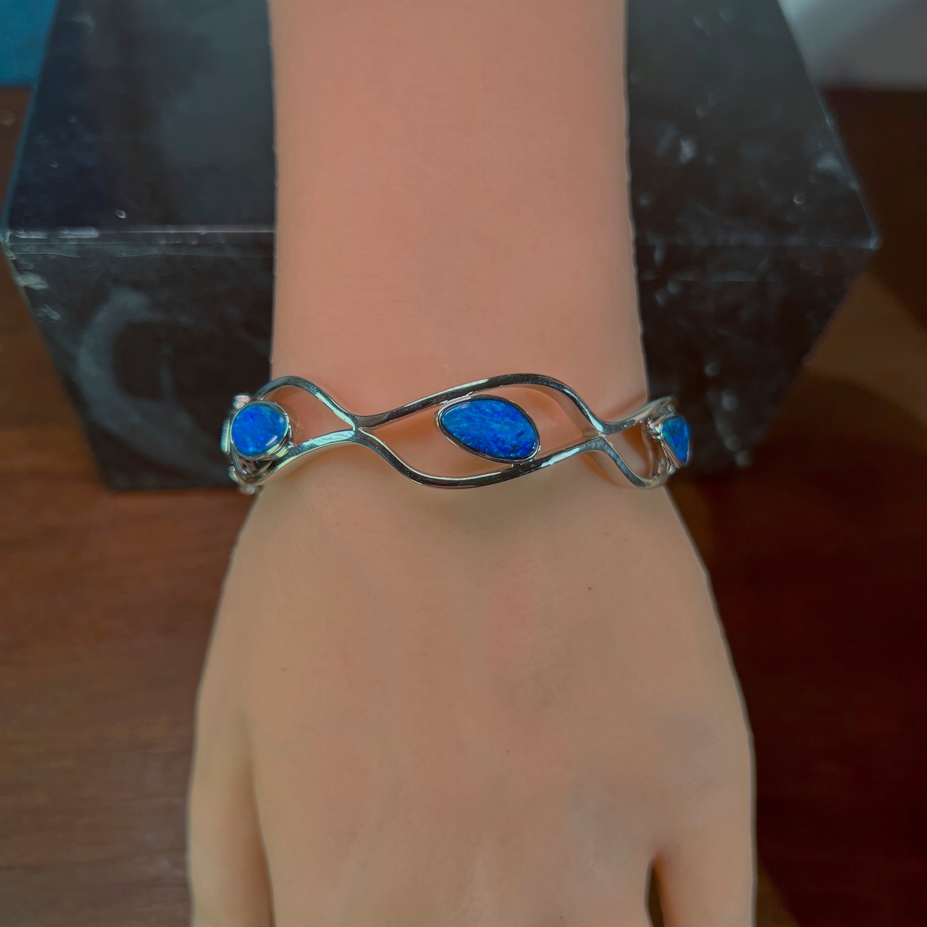 Wave cut-out silver bangle worn, showing how the opal doublet sits on the wrist