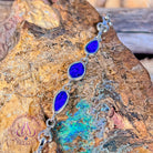 Sterling silver bracelet with three opal doublets against a weathered rock face, showing the linked stones