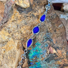Sterling silver bracelet with three opal doublets photographed in profile against rock, showing the bezel settings