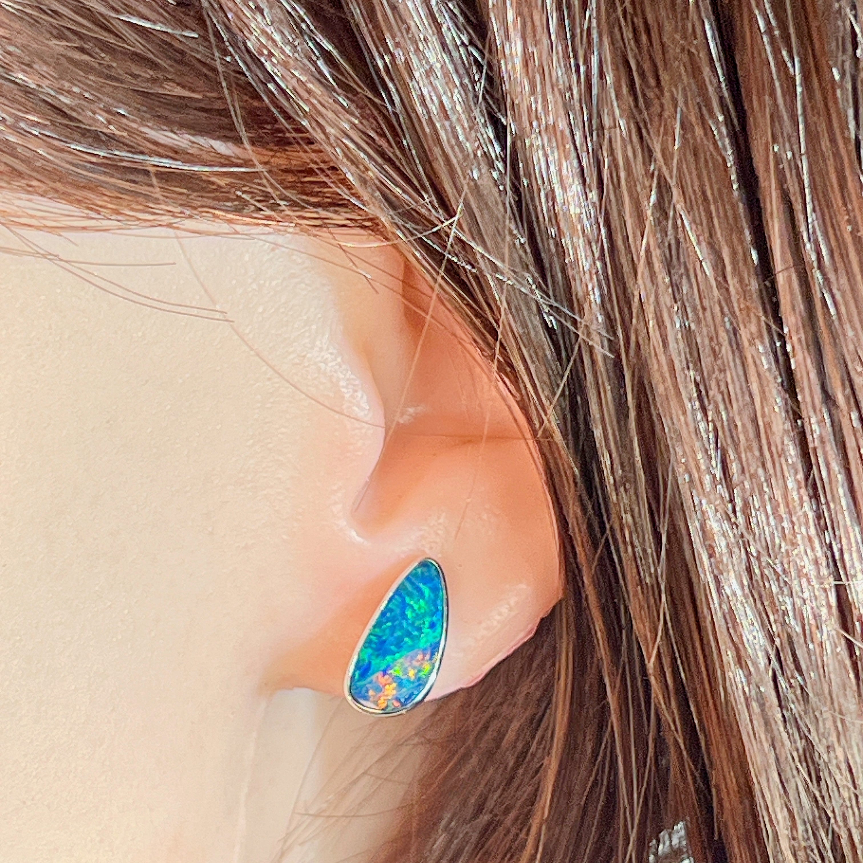 Freeform opal doublet stud earring worn on the ear, showing its scale on the earlobe