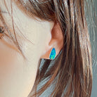 Blue and green opal doublet stud earring worn on the ear, viewed from behind