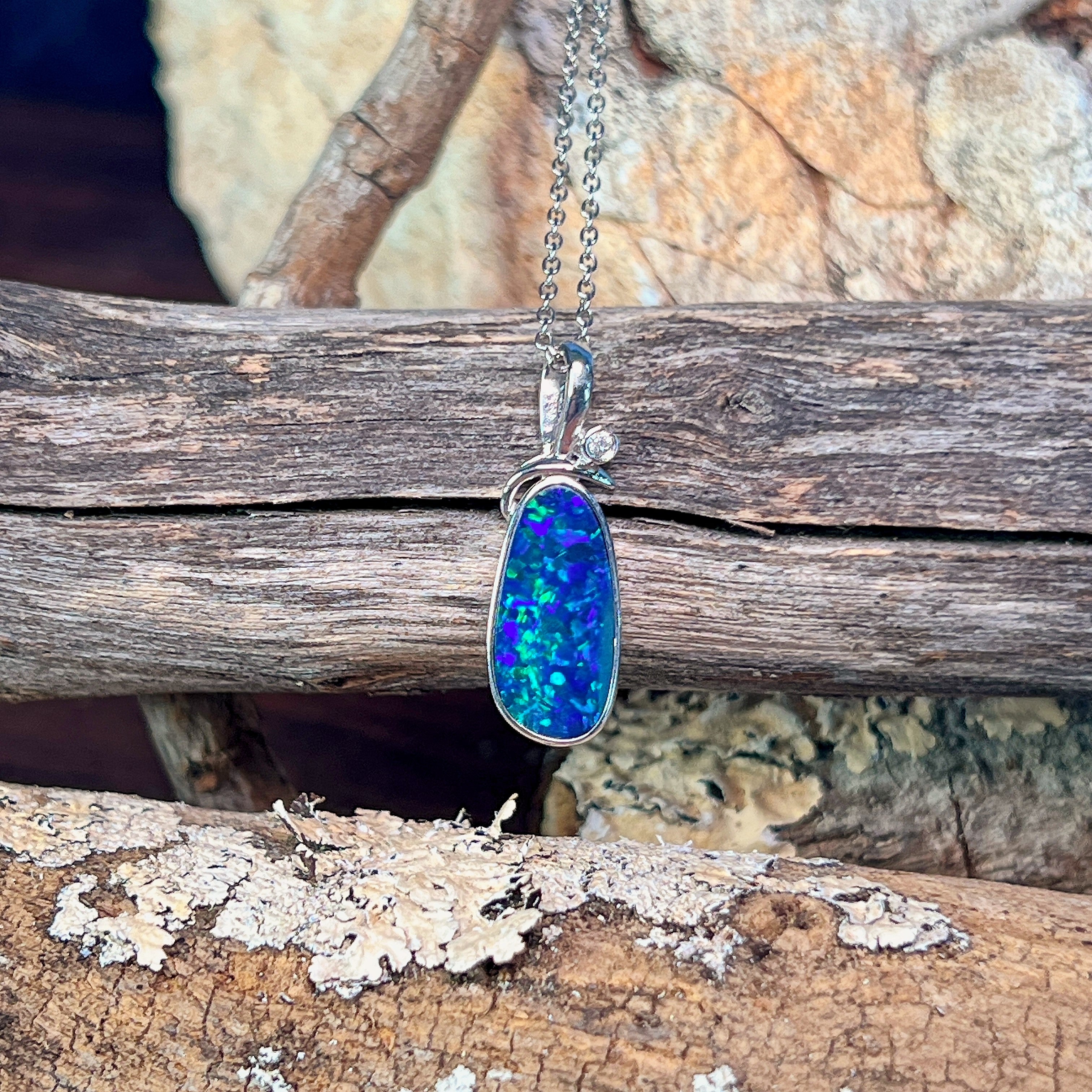 Sterling silver opal doublet pendant hanging against lichen-covered driftwood
