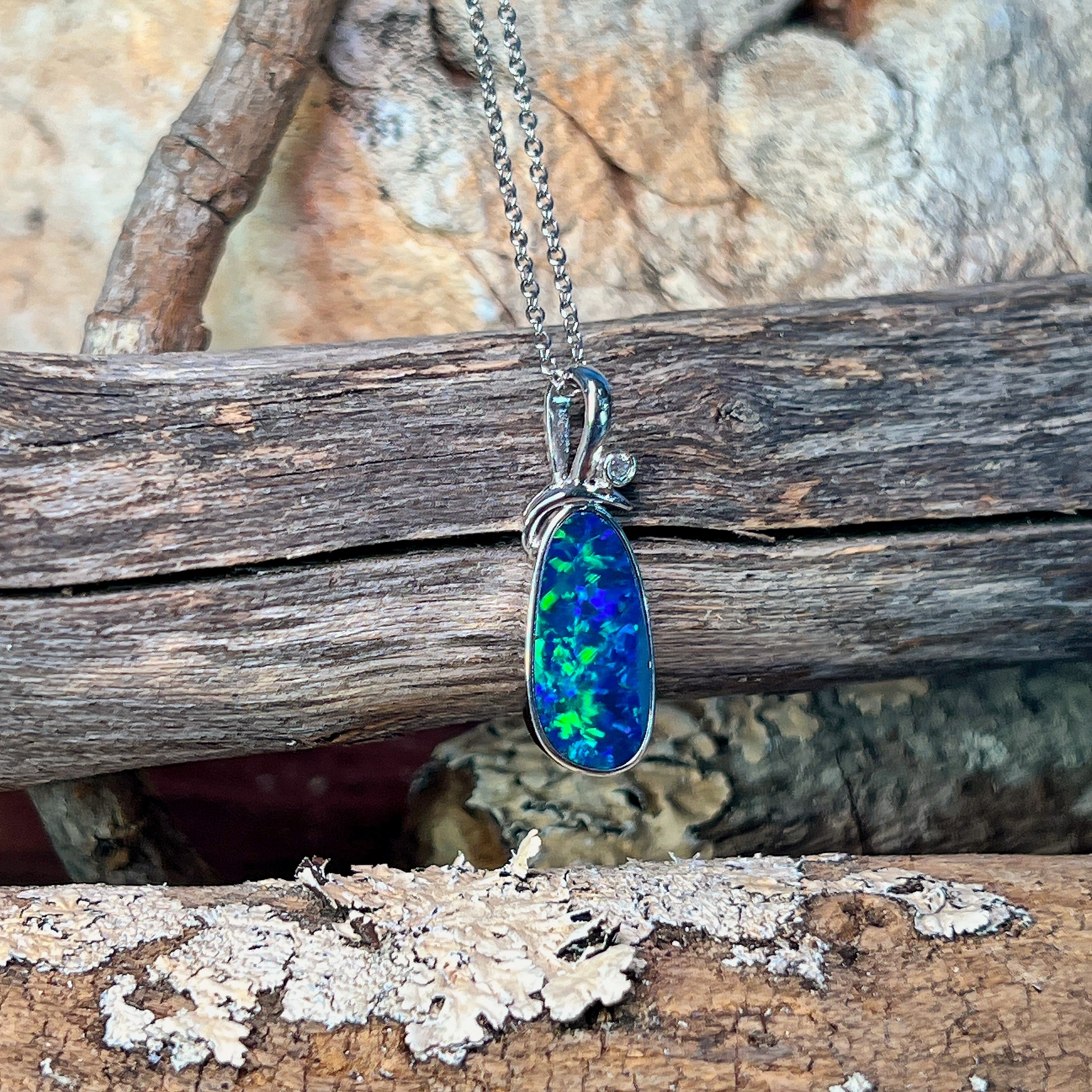 Freeform opal doublet pendant in silver showing bright green flash across the stone