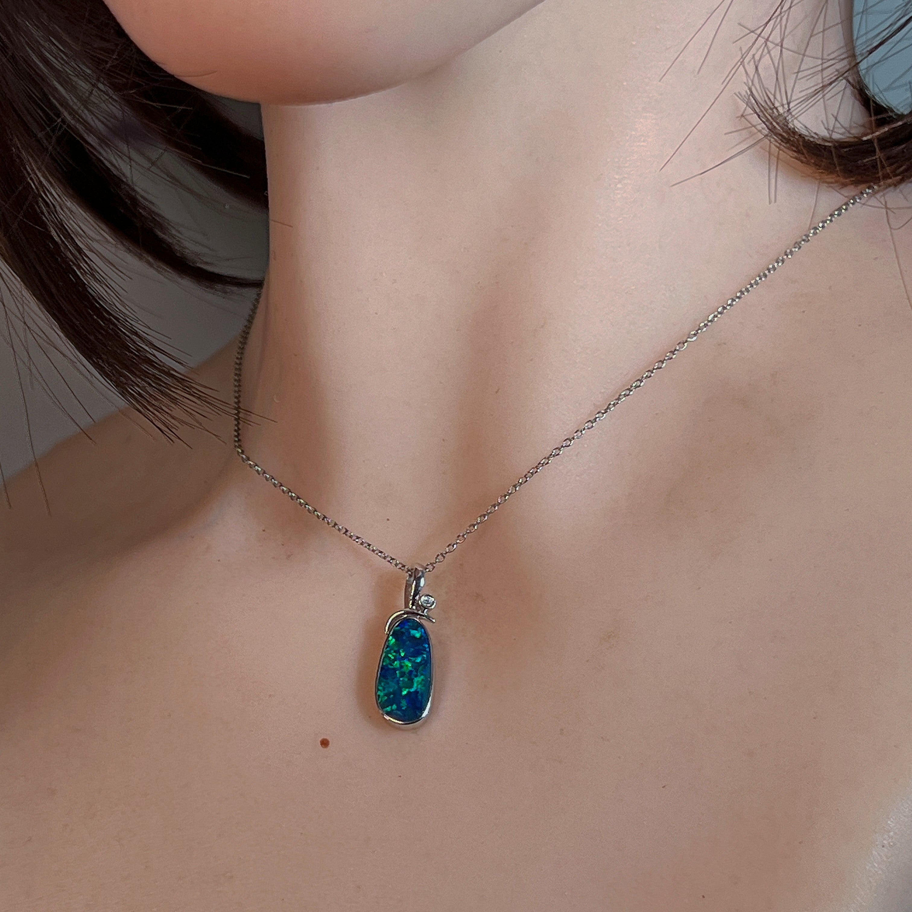 Freeform opal doublet pendant in silver worn on a fine chain at the neckline