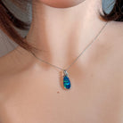 Blue-green opal doublet pendant worn at the neck, close view on the chain