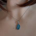 Blue-red opal doublet pendant worn at the neck, showing its scale on the collarbone