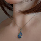 Freeform opal doublet pendant in silver worn on a fine chain at the neckline
