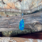 Sterling silver freeform opal doublet pendant hanging against weathered driftwood