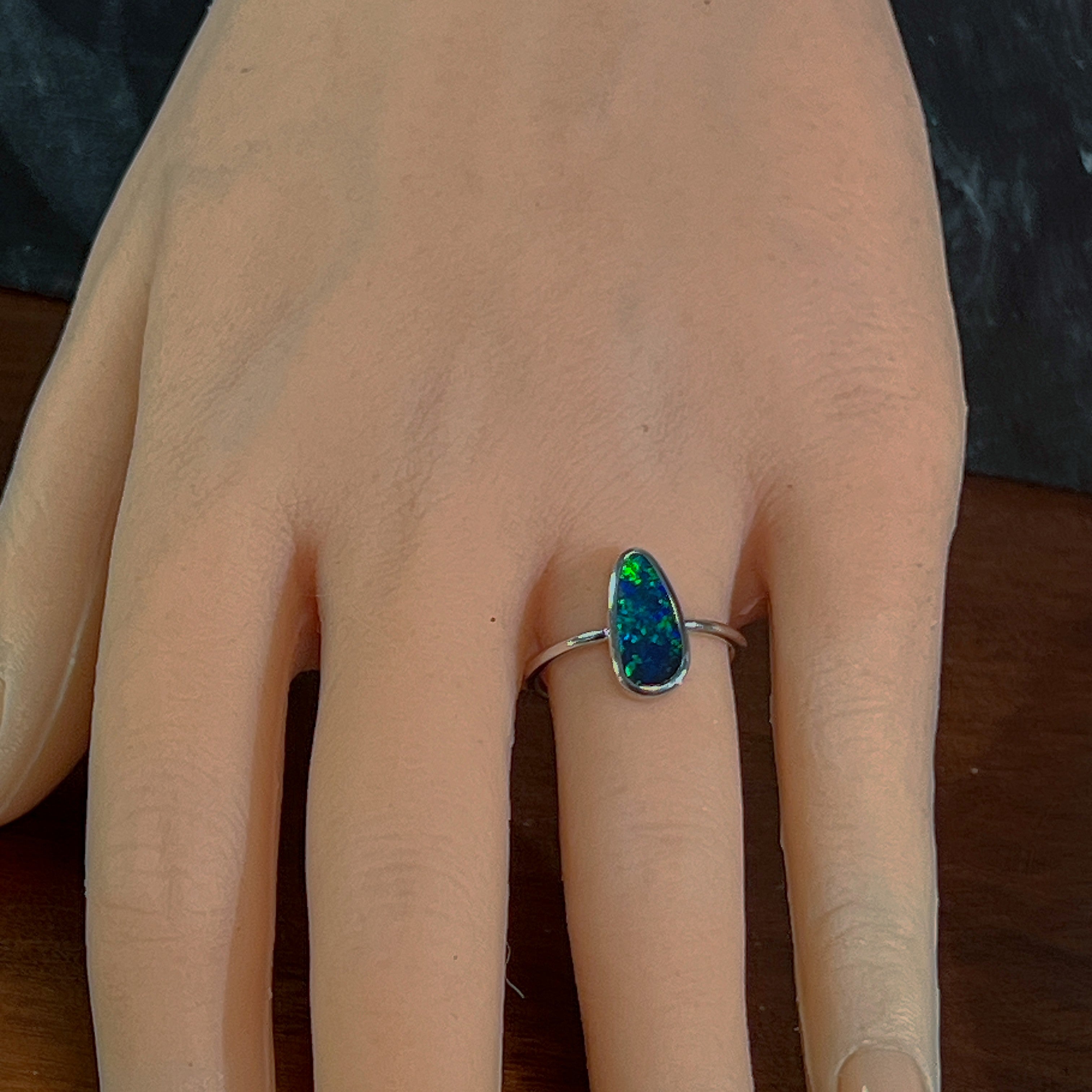 Freeform opal doublet ring worn on the hand, showing its length on the finger