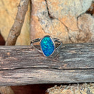 Freeform opal doublet ring in silver resting on weathered driftwood