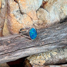 Freeform opal doublet ring in silver on driftwood against Australian sandstone