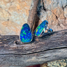 Blue and green opal doublet studs in silver bezel settings, angled to catch the play-of-colour