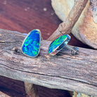 Sterling silver opal doublet stud earrings on driftwood, showing the bezel rim and posts