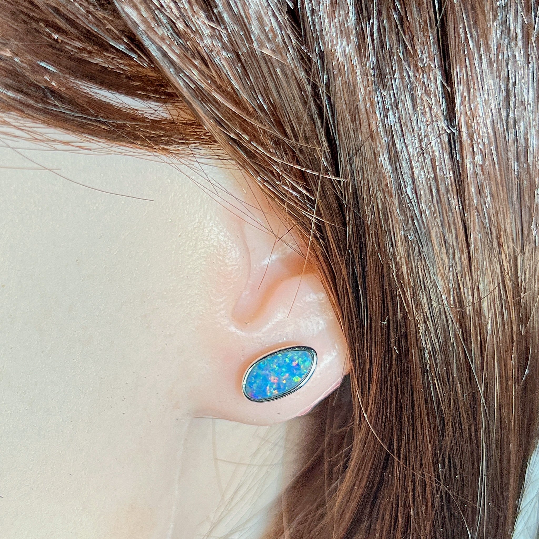Australian opal doublet earrings worn on the ear, red, blue, yellow and green play-of-colour
