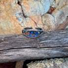 Horizontal oval opal doublet ring in silver resting on weathered driftwood