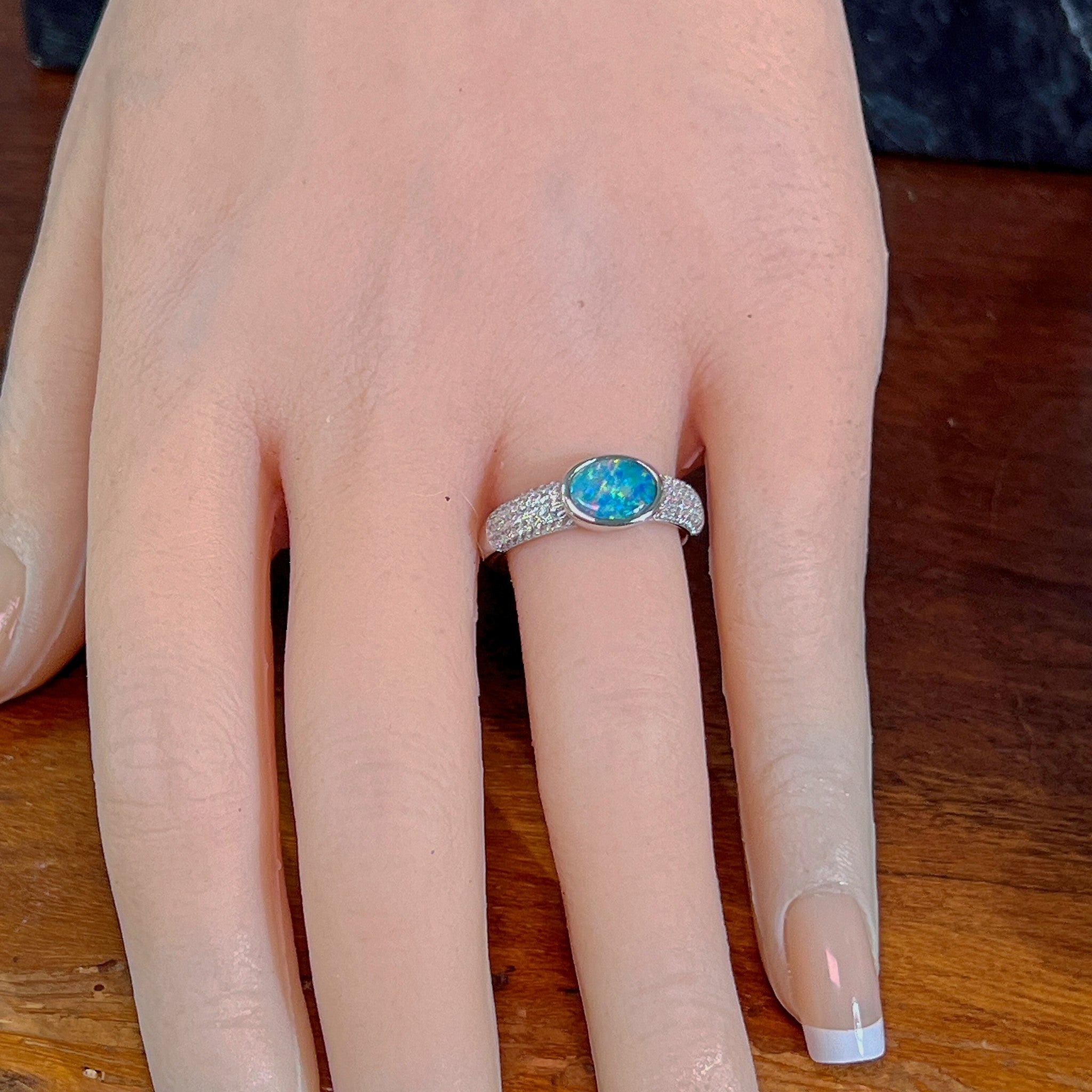 Oval opal doublet ring on a pave silver band worn on the hand, full view across the fingers