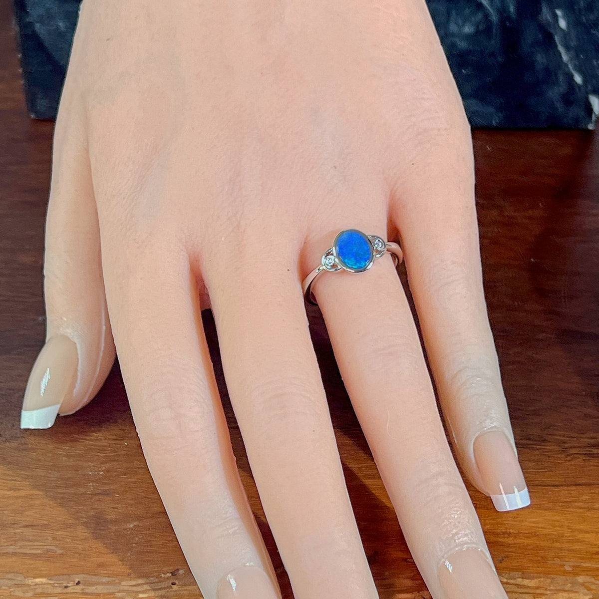 Blue opal doublet ring in silver worn on the hand, full view across the fingers