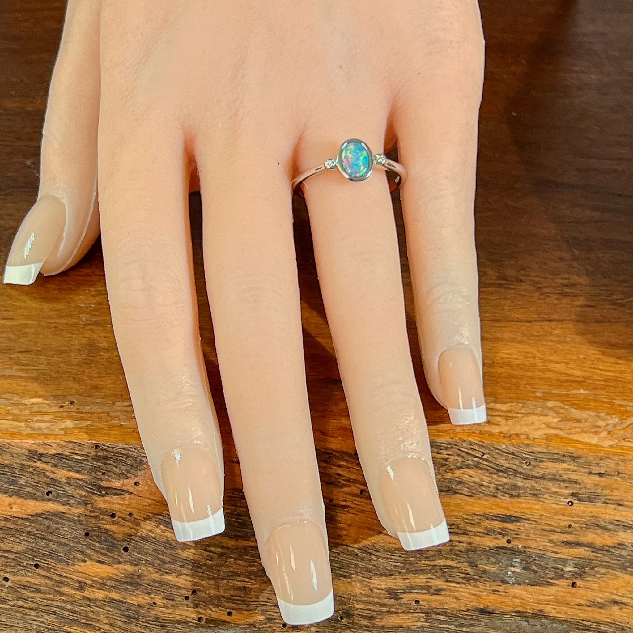 Oval opal doublet ring in silver worn on the hand, full view across the fingers