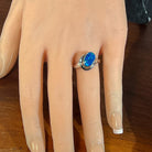 Deep blue opal doublet ring in silver worn on the hand, viewed across the fingers