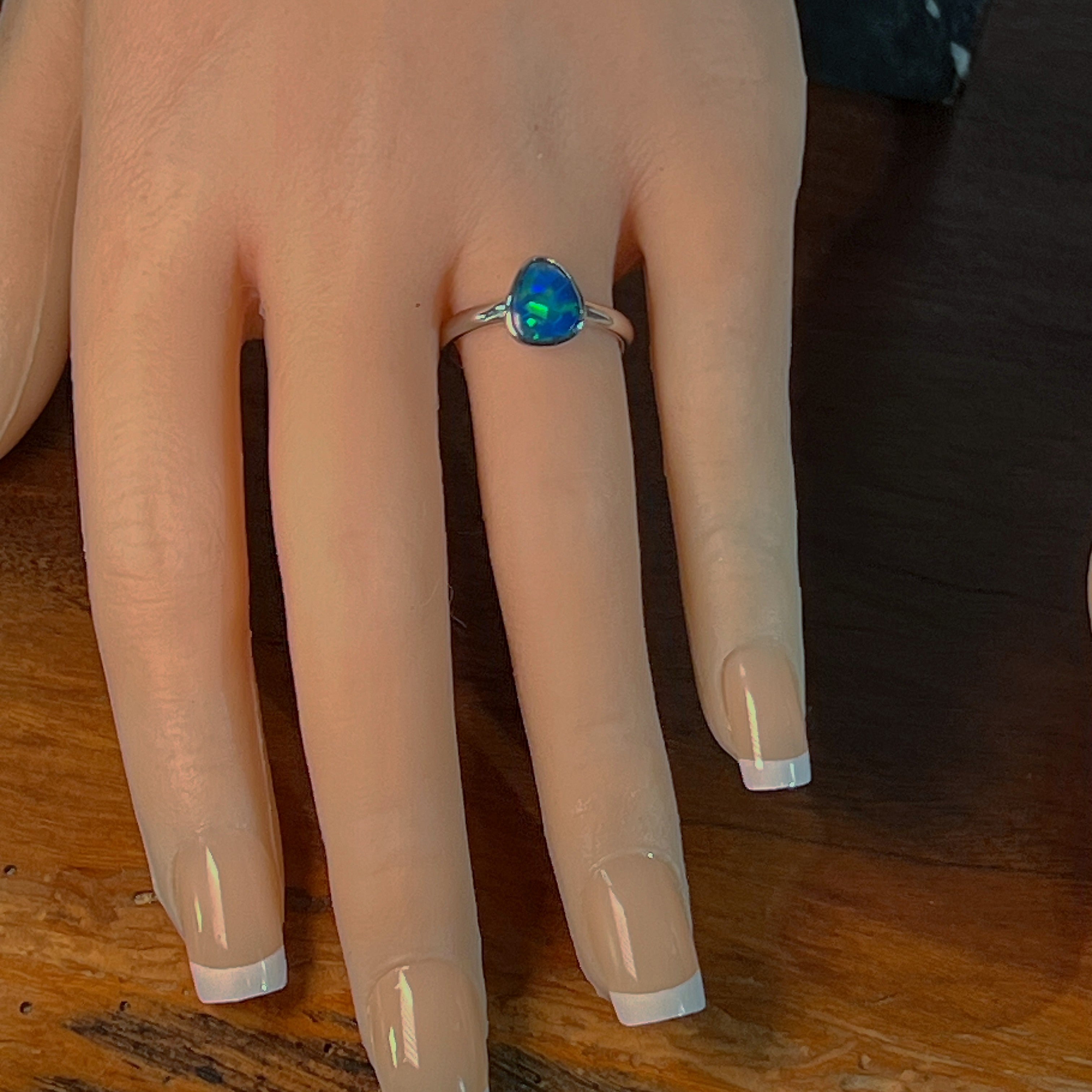 Blue-green pear opal doublet ring worn on the hand, viewed across the fingers