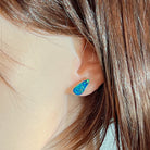 Blue-green opal doublet stud earring worn on the ear beneath loose hair