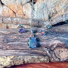 Silver claw-set opal triplet pendant and matching studs on weathered driftwood
