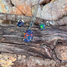 Sterling silver claw-set opal triplet jewellery set arranged on driftwood