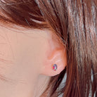 Claw-set opal triplet stud earring worn on the ear, showing its scale on the earlobe
