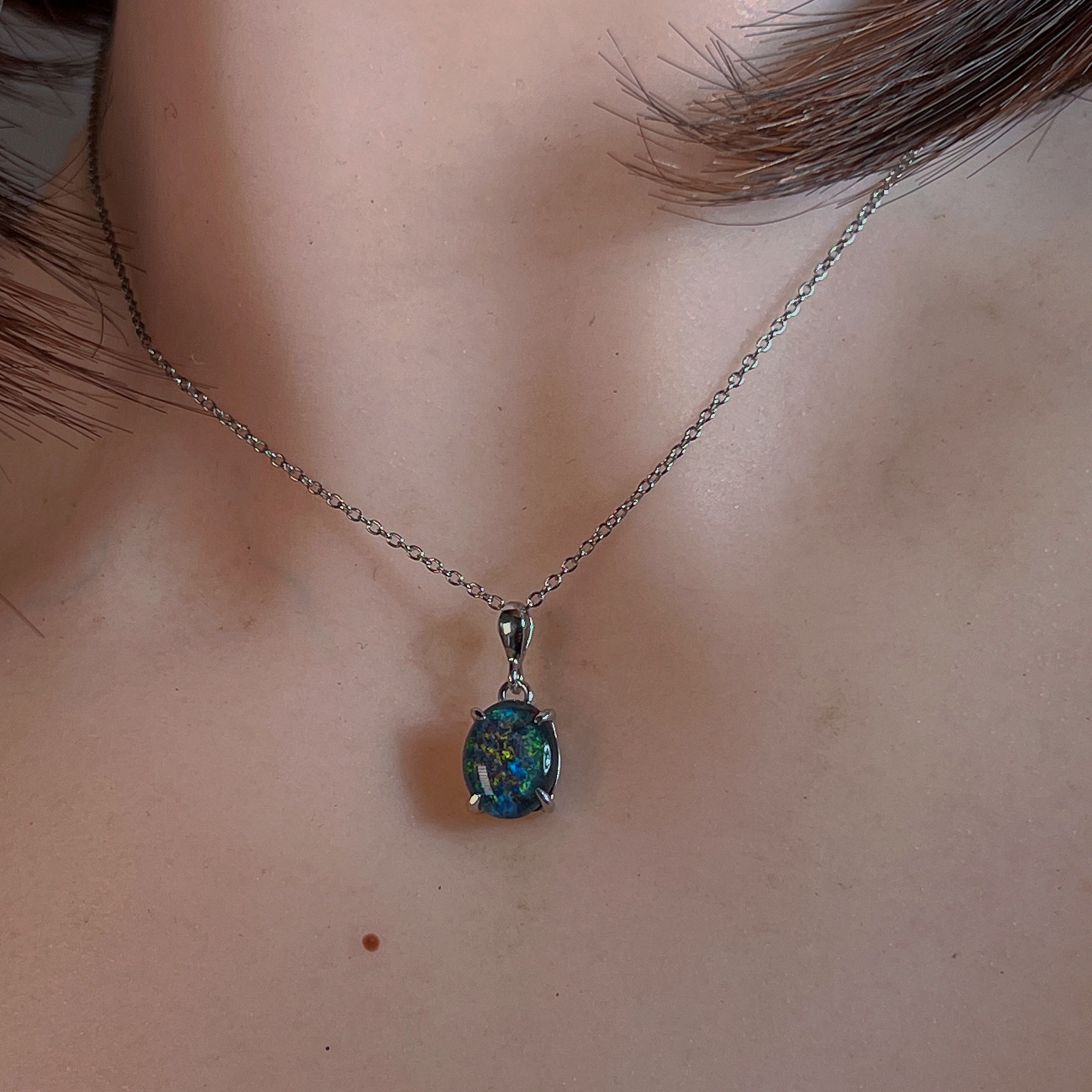 Claw-set opal triplet pendant worn at the neck on a fine silver chain