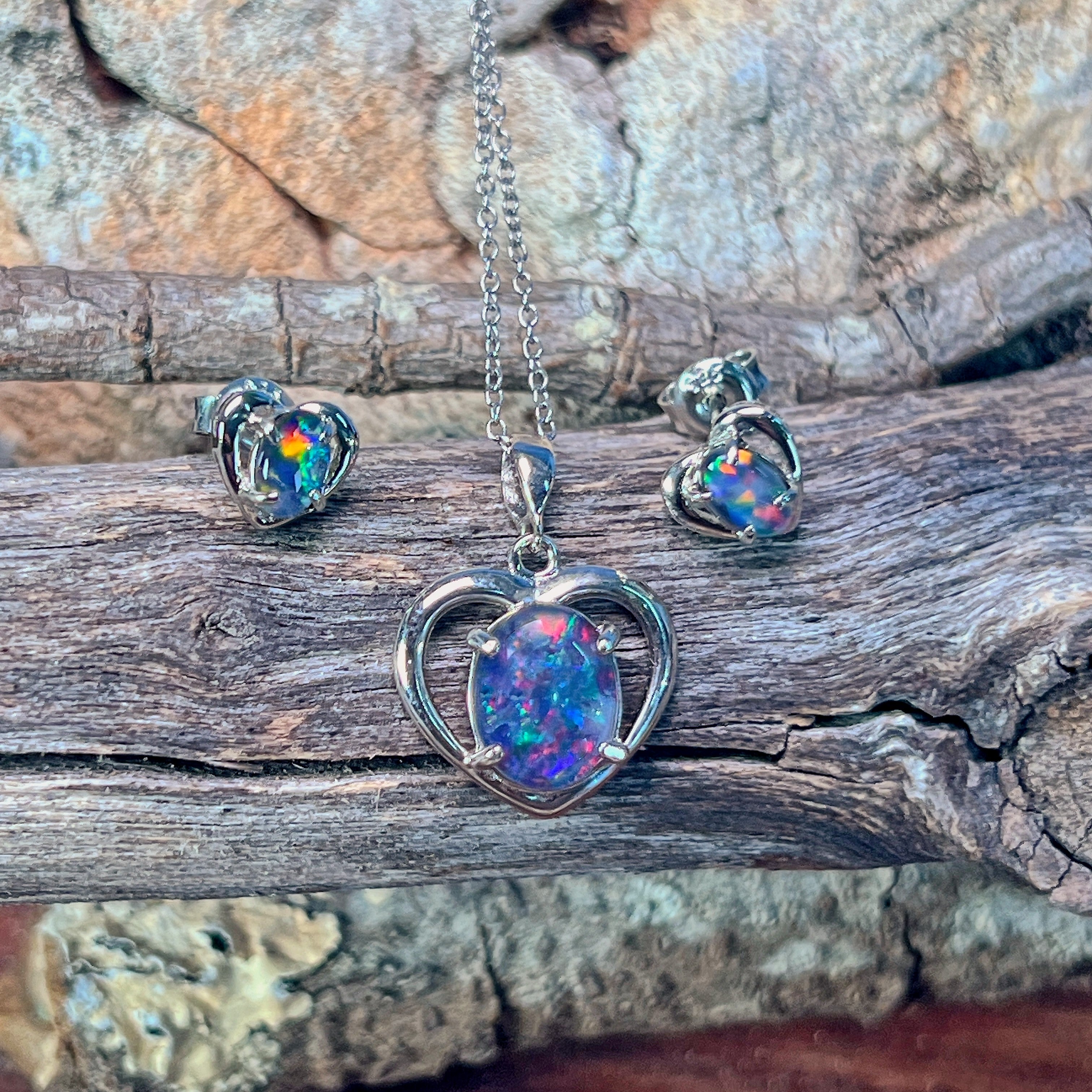 Sterling silver heart opal triplet jewellery set arranged on driftwood