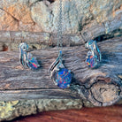 Opal triplet pendant and earrings in silver, close view of the swirl setting