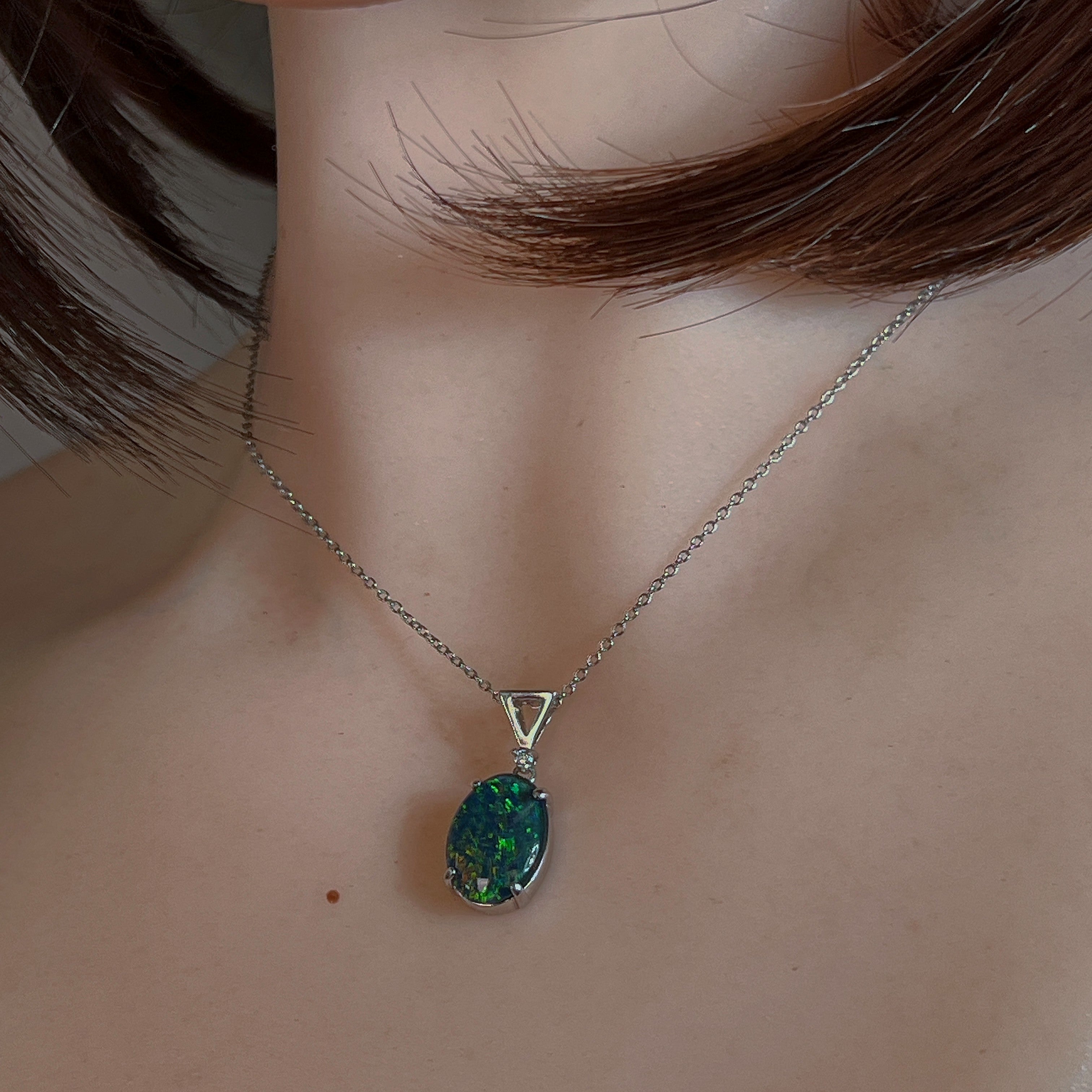 Oval opal triplet pendant in sterling silver worn on a fine chain at the neckline