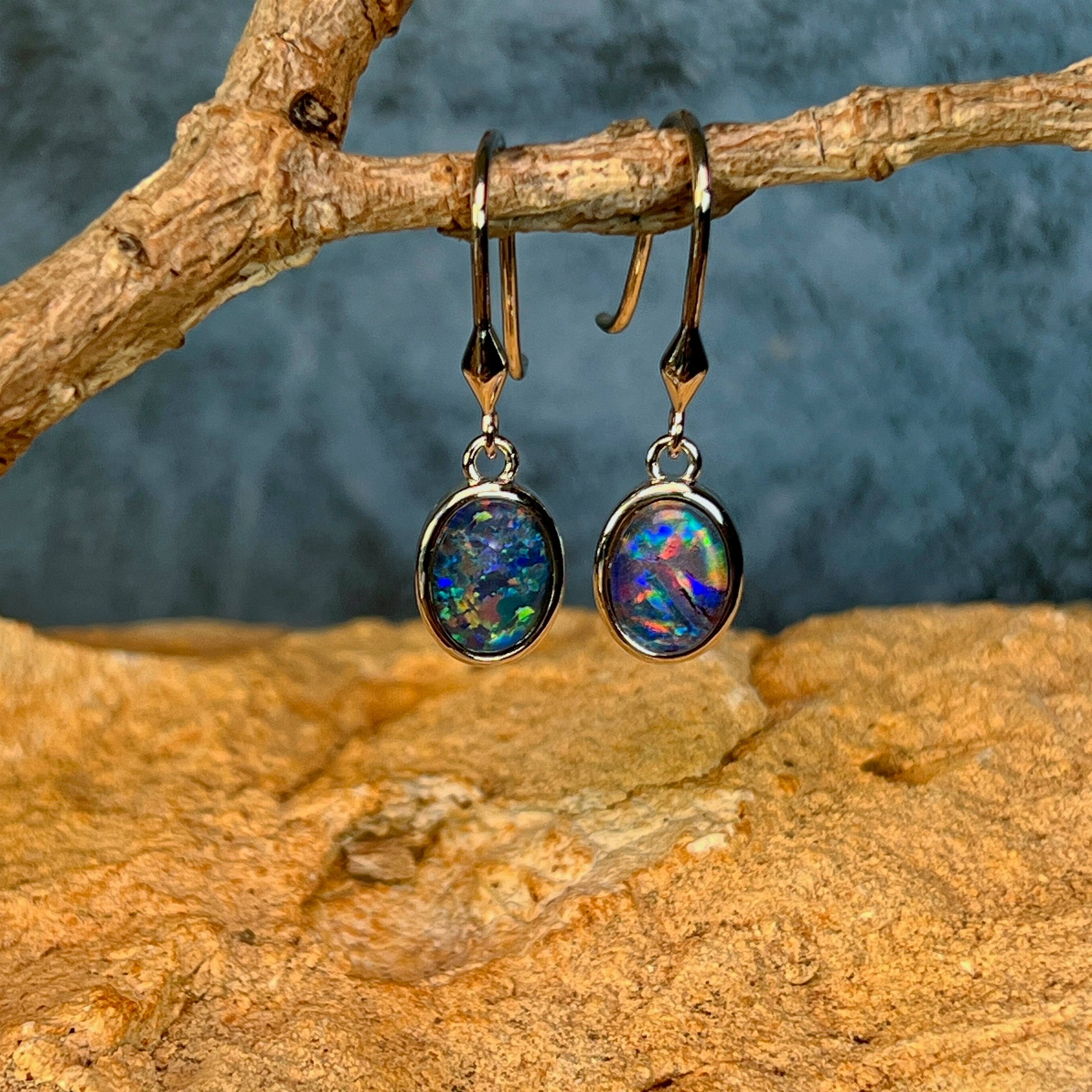 Sterling silver opal triplet dangling earrings hanging from a driftwood branch