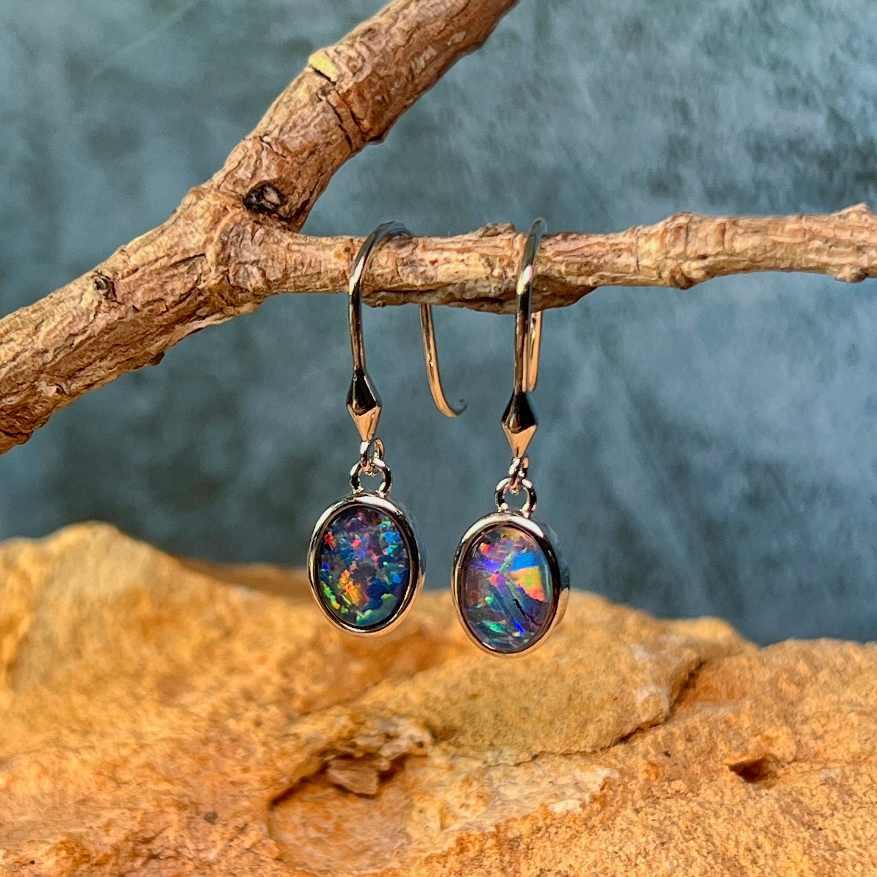 Close view of the oval Australian opal triplets in sterling silver bezel settings, hanging on driftwood