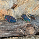 Pair of opal triplet cufflinks in silver resting on weathered driftwood