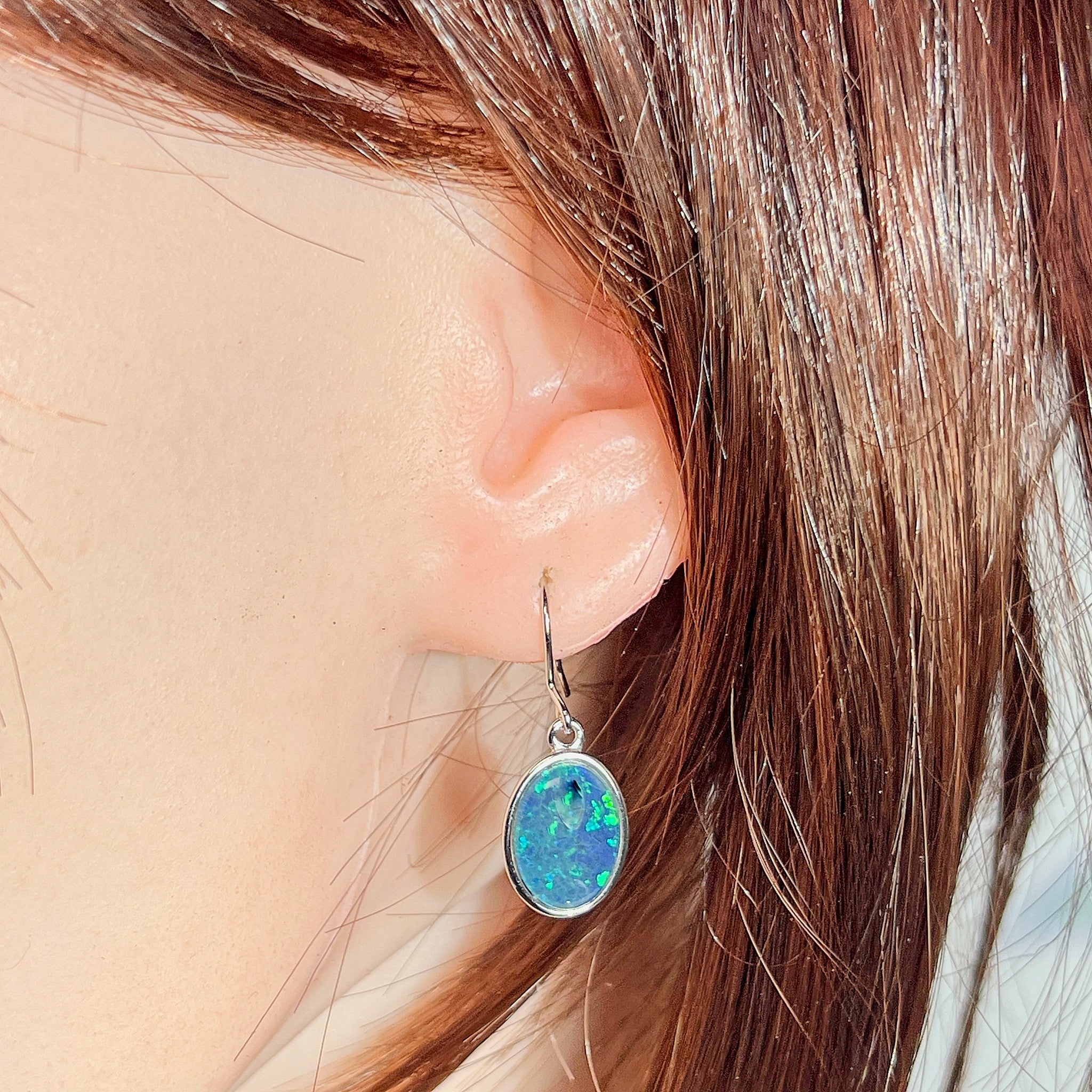oval Australian opal triplet earrings in sterling silver, worn on the ear