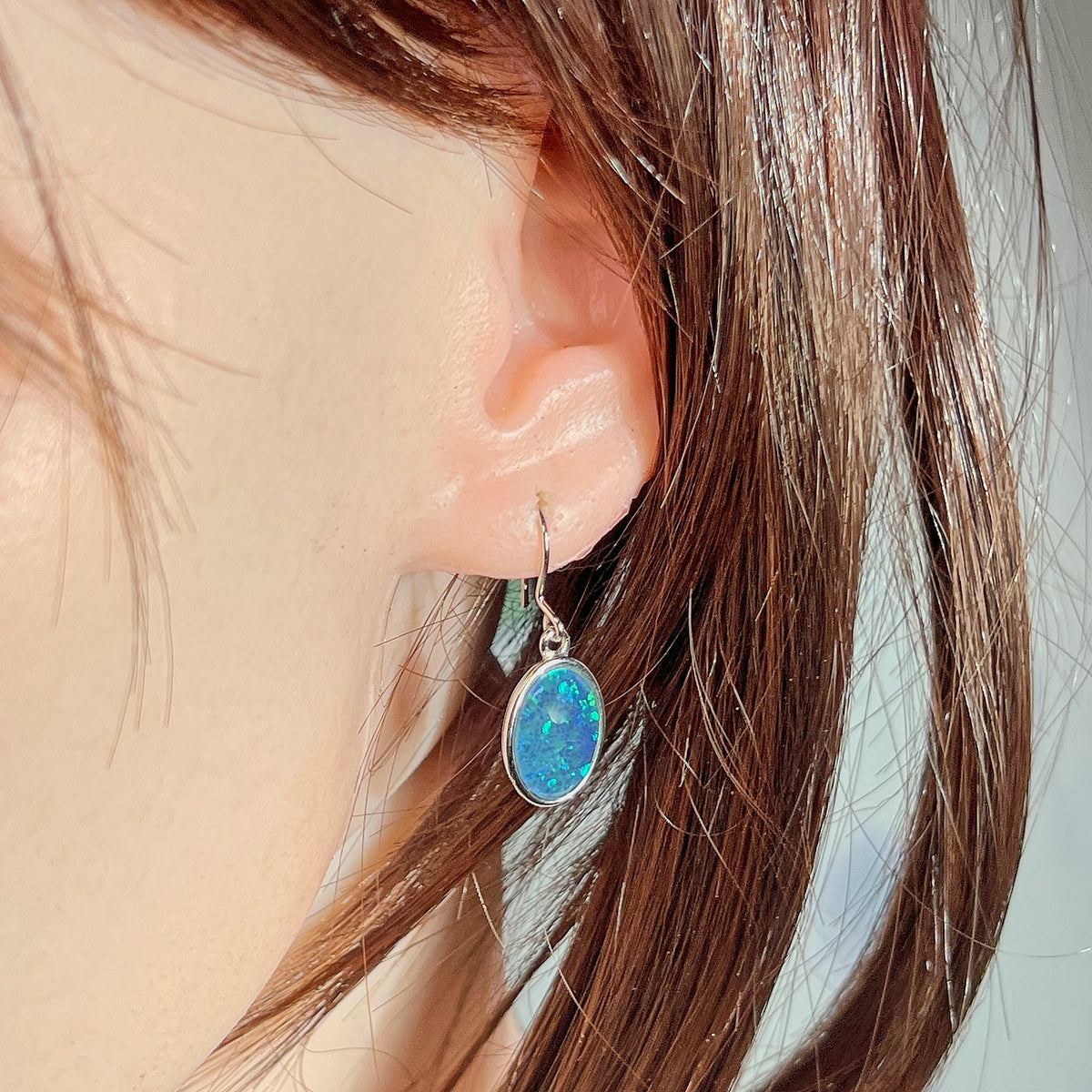 Australian opal triplet earrings worn on the ear, blue and green play-of-colour
