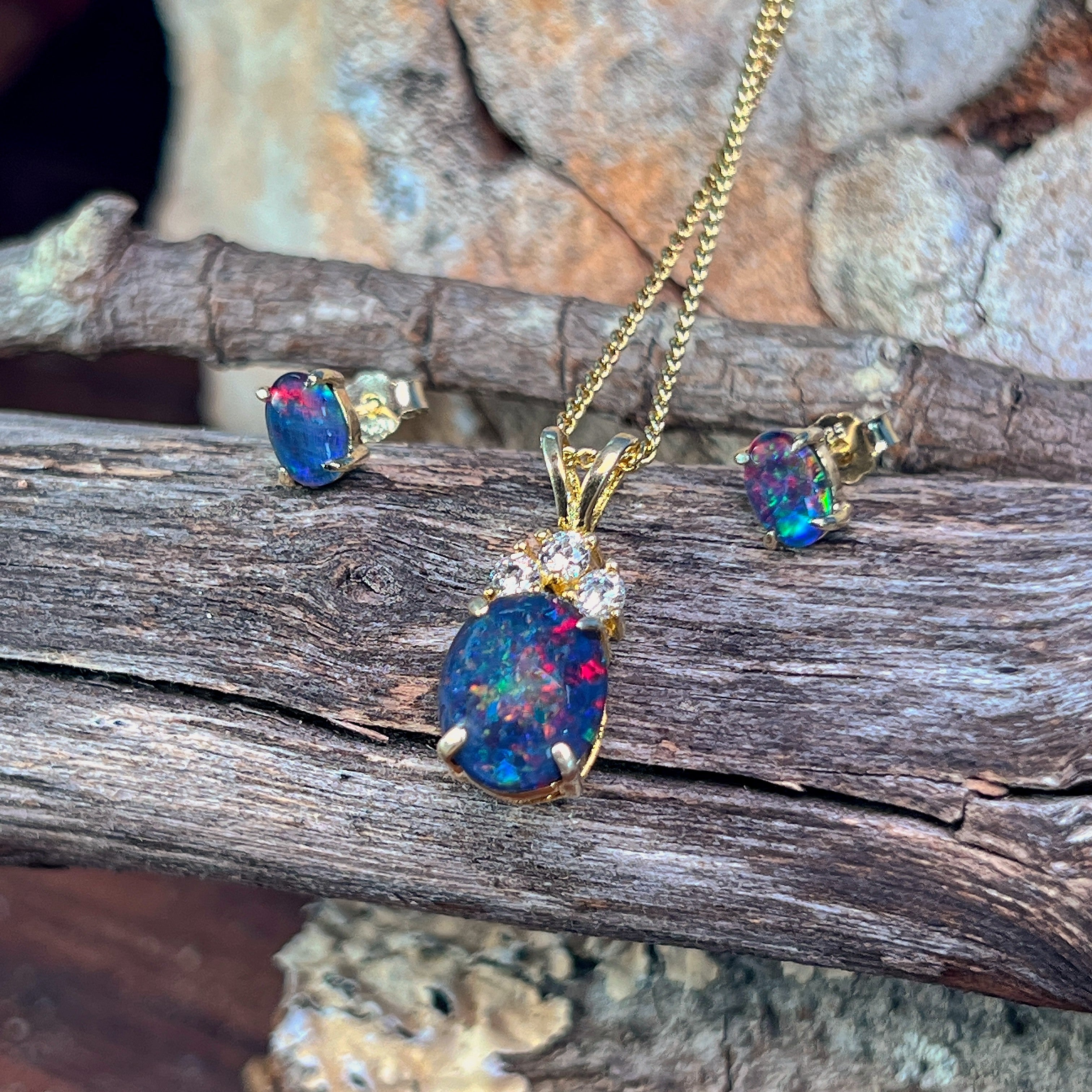 Yellow gold-plated opal triplet jewellery set arranged on weathered driftwood