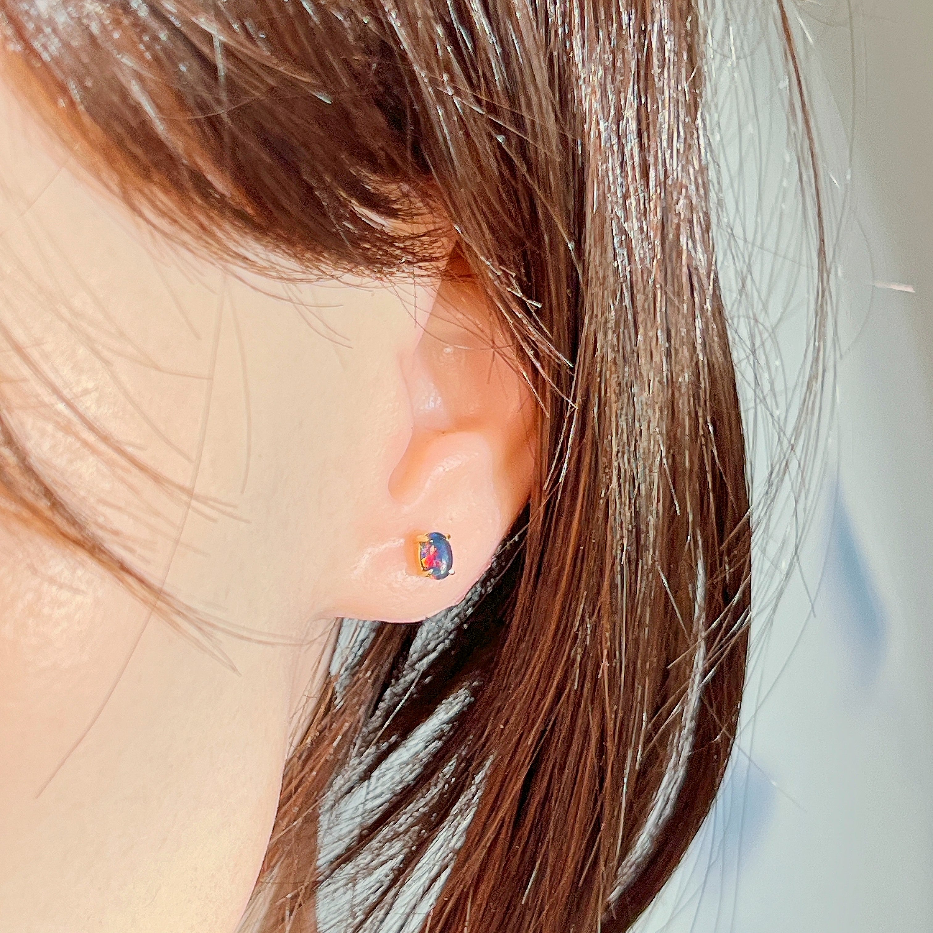 Opal triplet stud in gold-plated silver worn on the ear, side profile view
