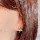 Opal triplet cluster stud earring worn on the ear, showing its scale on the earlobe