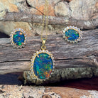 Halo-set opal triplet pendant and earrings in yellow gold-plated silver on driftwood