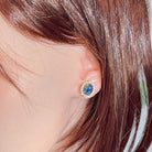 Opal triplet halo stud earring worn on the ear beneath loose hair