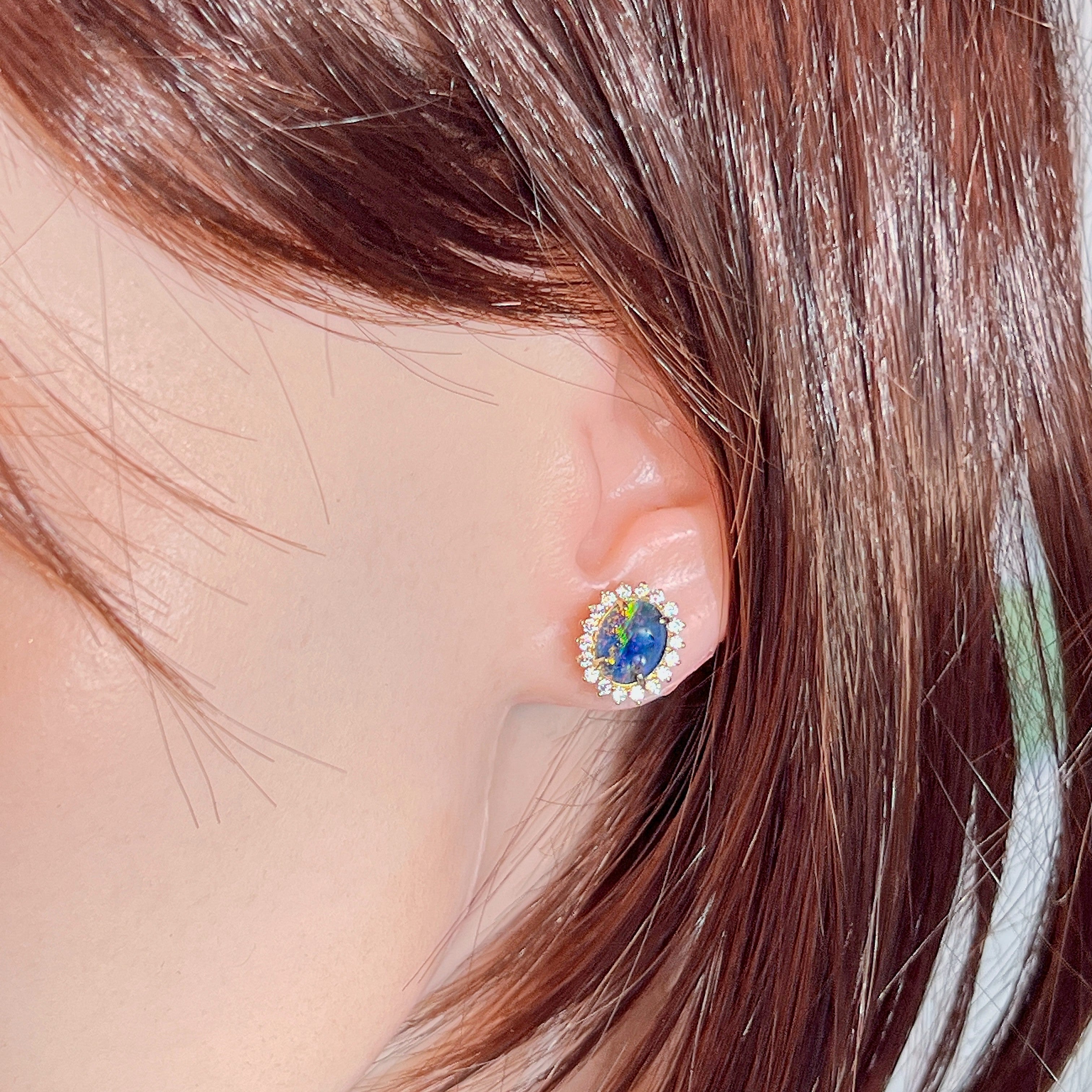 Opal triplet halo stud earring worn on the ear beneath loose hair